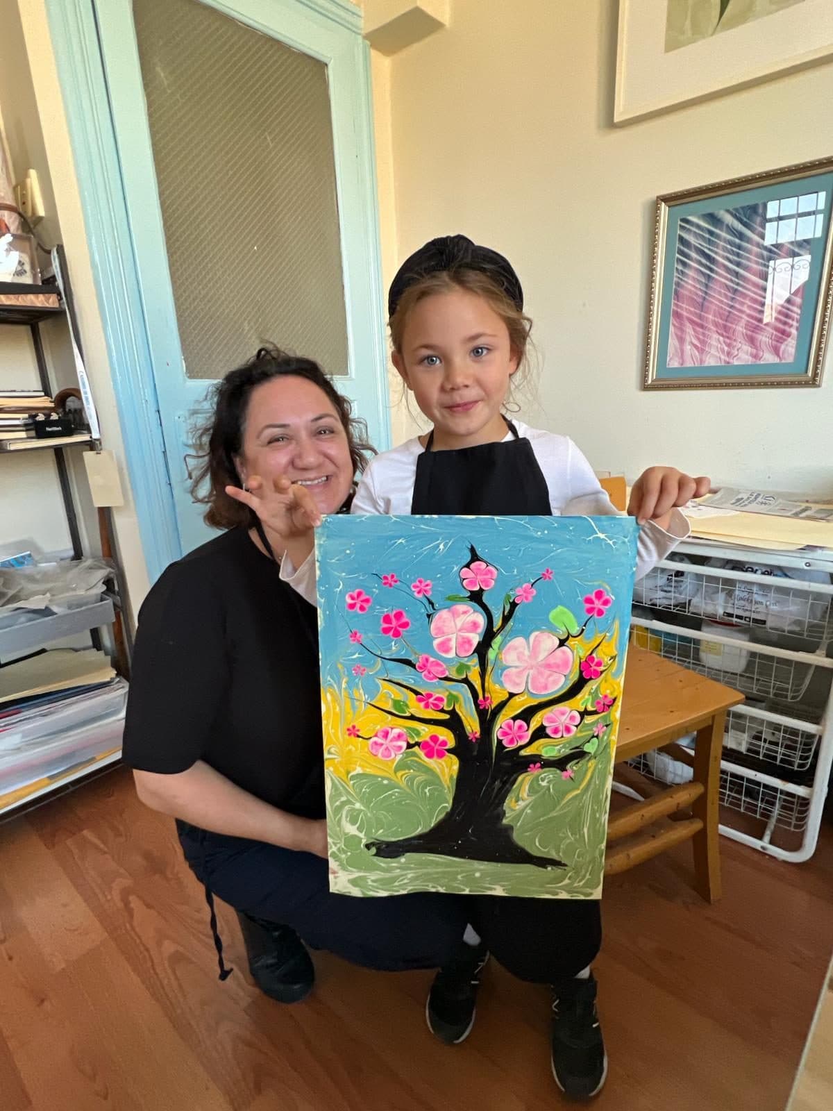 A girl holding a gold starburst marbling artwork