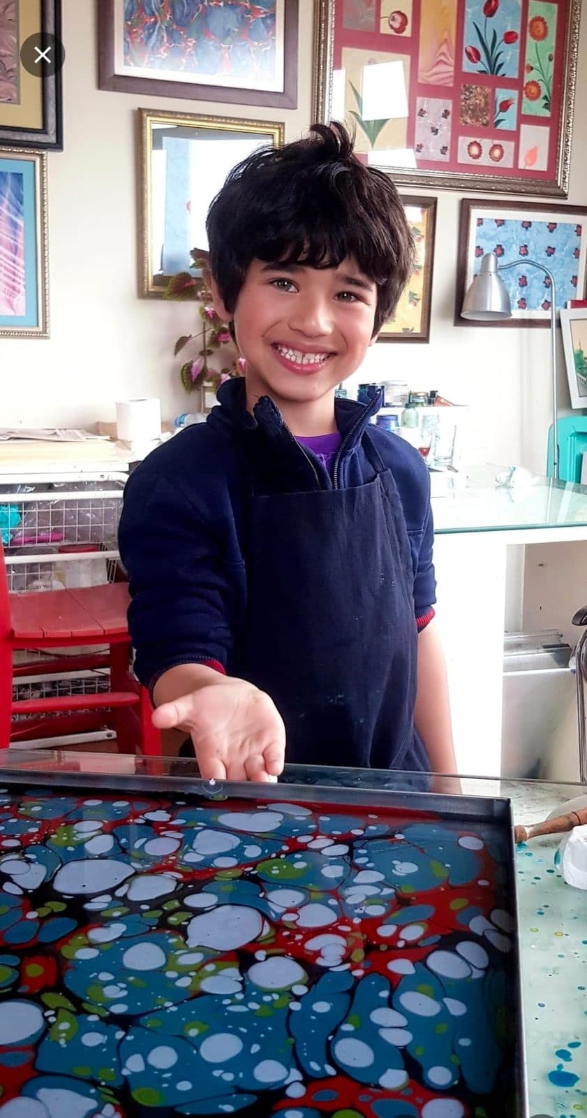 A young boy beside a freshly marbled paper tray